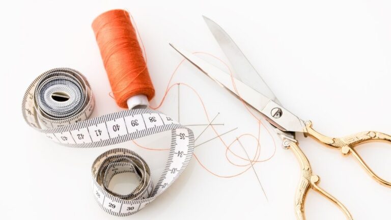 tesoura, agulha e linha de costura e régua de medida